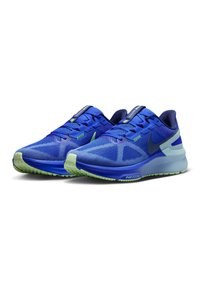 Scarpe da ginnastica blu con tomaia in rete, motivo testurizzato, accenti verdi e suola imbottita. Presentano una punta arrotondata e un design con lacci.