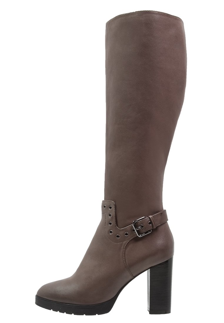 Bota de cuero marrón hasta la rodilla con un tubo ancho, detalle de hebilla y acentos de tachuelas. Cuenta con un tacón grueso negro y textura suave.
