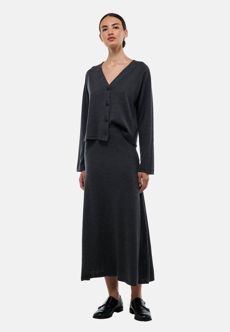 Cardigan en tricot gris foncé avec un col en V et trois boutons, associé à une jupe longue assortie. Possède une texture lisse et une coupe décontractée.