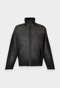 Tmavě šedá bunda na zip s vysokým límcem, dlouhými rukávy, bočními kapsami a nenápadným logem na levé části hrudi na bílém pozadí.