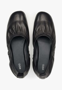 Czarne skórzane buty wsuwane z okrągłym noskiem, zebranym wzorem z przodu i miękką podszewką. Logo marki widoczne w środku.