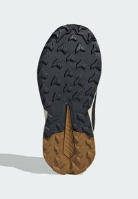 Semelle de chaussure en caoutchouc noire et marron avec des motifs en forme de triangle, présentant des surfaces texturées et une rainure centrale pour une traction et une stabilité optimales.