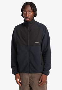 Fleece jacket with a zip front, featuring a dark navy body and black panels. Includes a small logo on the chest and zippered pockets.