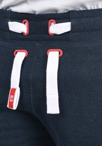 Marineblauwe sweatpants van een katoenmix, met witte trekkoorden die zijn vastgezet met rode lussen en een klein rood label met "SLD."