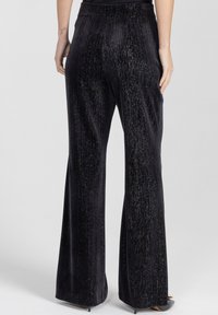 Czarne, plisowane spodnie wykonane z teksturowanego materiału z delikatnymi błyszczącymi akcentami, z rozszerzanym dołem i elastycznym pasem.