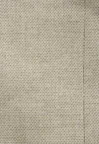 Tela de tejido beige con una textura densa, que presenta un sutil patrón de cuadrícula y un acabado suave, adecuado para tapicería o prendas de vestir.