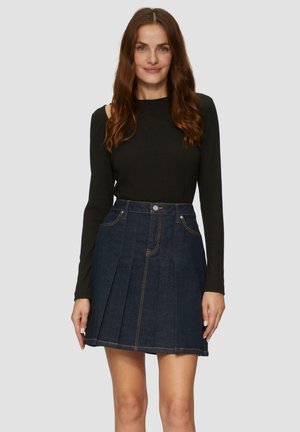Donkerblauwe denim rok met geplooid ontwerp, met voorzakken, een knoopsluiting en contrasterende oranje stikdetails. Model draagt een zwarte top.