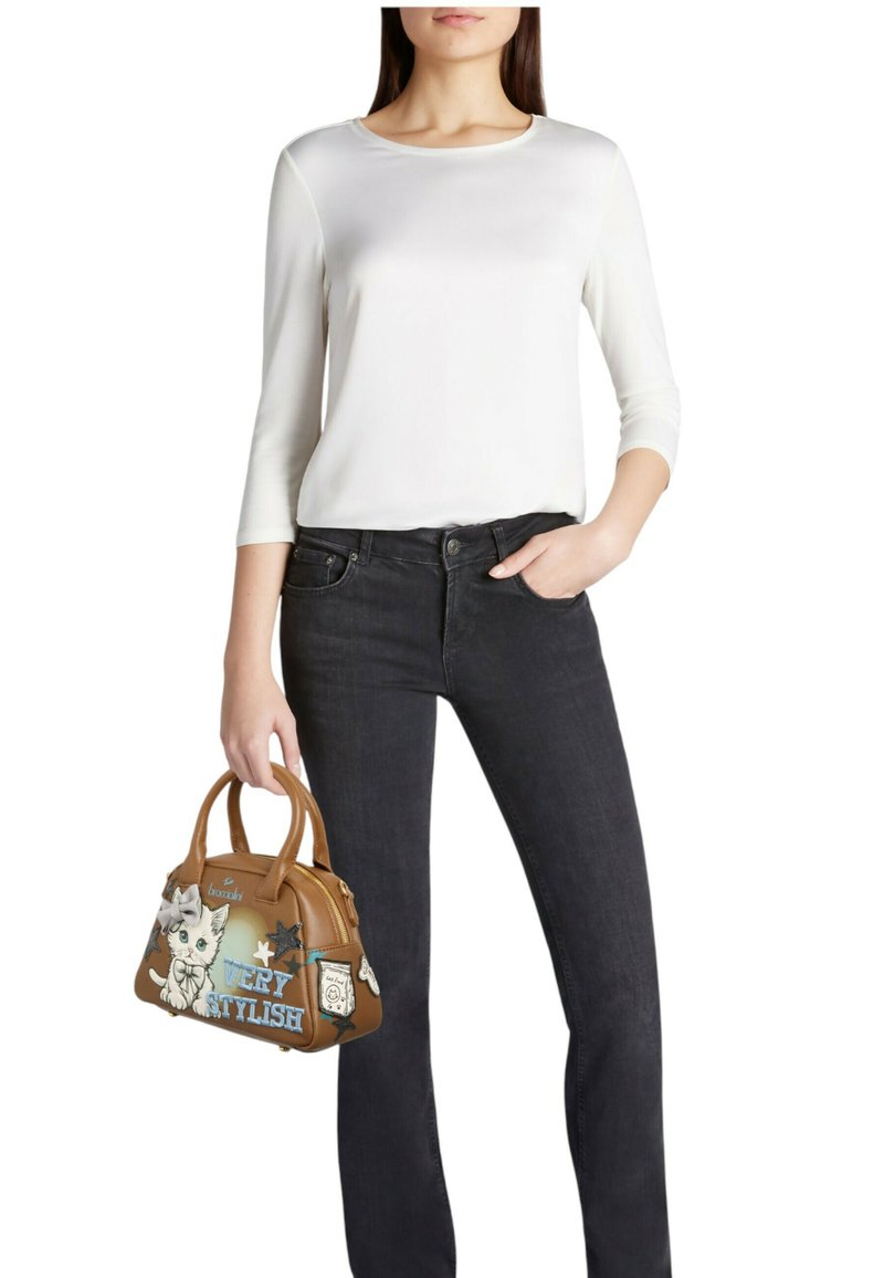 Borsa marrone con design grafico, illustrazione di gatto e testo "VERY STYLISH". Il modello indossa una maglia bianca a maniche lunghe e jeans neri.