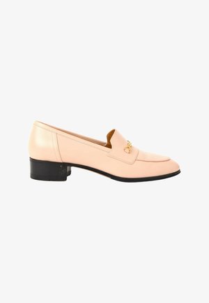 Mocassin en cuir rose clair à petit talon, semelle noire et petit emblème décoratif doré sur le devant.
