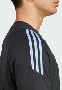 Sort atletisk T-shirt med lysblå tre-stribe design på skuldrene; lavet af bomuld, rund hals, tætsiddende i torsoen.