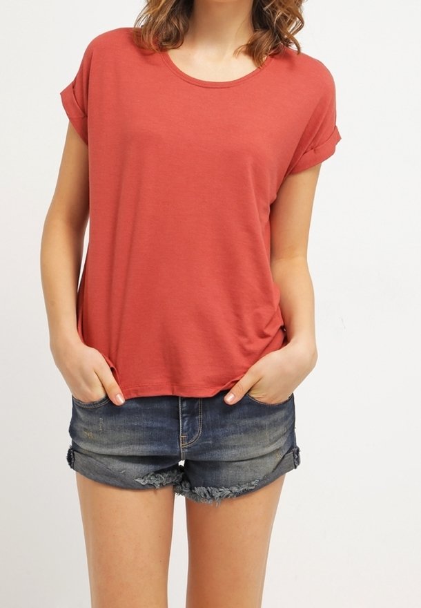 T-shirt rouge rouille à manches courtes avec un col arrondi, coupe décontractée et poignets retroussés, associé à un short en denim effiloché.