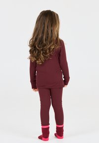 Bordeaux langmouwtop en bijpassende maillot, gedragen met rode en roze sokken. Glad textuur en aansluitend ontwerp. Kind gezien vanaf de achterkant.