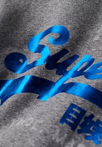 Tela gris con una textura suave, que presenta letras y acentos azules brillantes, mostrando un diseño gráfico estilizado.