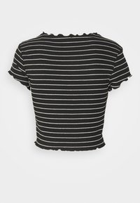 Lyhythihainen crop-top mustavalkoisilla raidoilla, joissa on teksturoitu kangas ja aaltoilevat reunat. Topissa on pyöreä kaula-aukko ja tiukka malli.