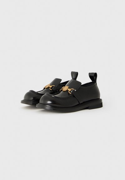 Svarta läder slip-on loafers med rundade tår och guldfärgad metalldetalj framtill, med hälpulltabbar och låga, platta sulor.