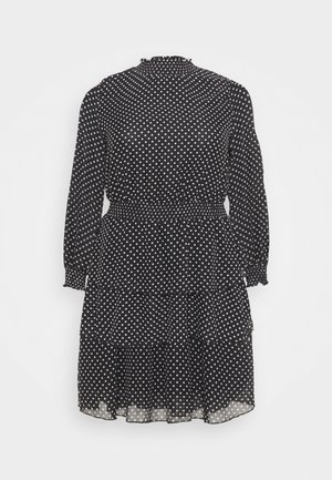 Vestito nero a maniche lunghe con pois bianchi, collo alto, vita e polsini arricciati e gonna a balze plissettata.