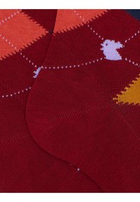 Red patterned socks featuring a diamond design with orange, yellow, and dark blue accents. Smooth texture with reinforced toe and heel.