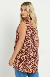 Mouwloze tuniek in tan met burgundy abstract patroon, met een ontspannen pasvorm, ronde hals en subtiele plooi detail aan de achterkant.