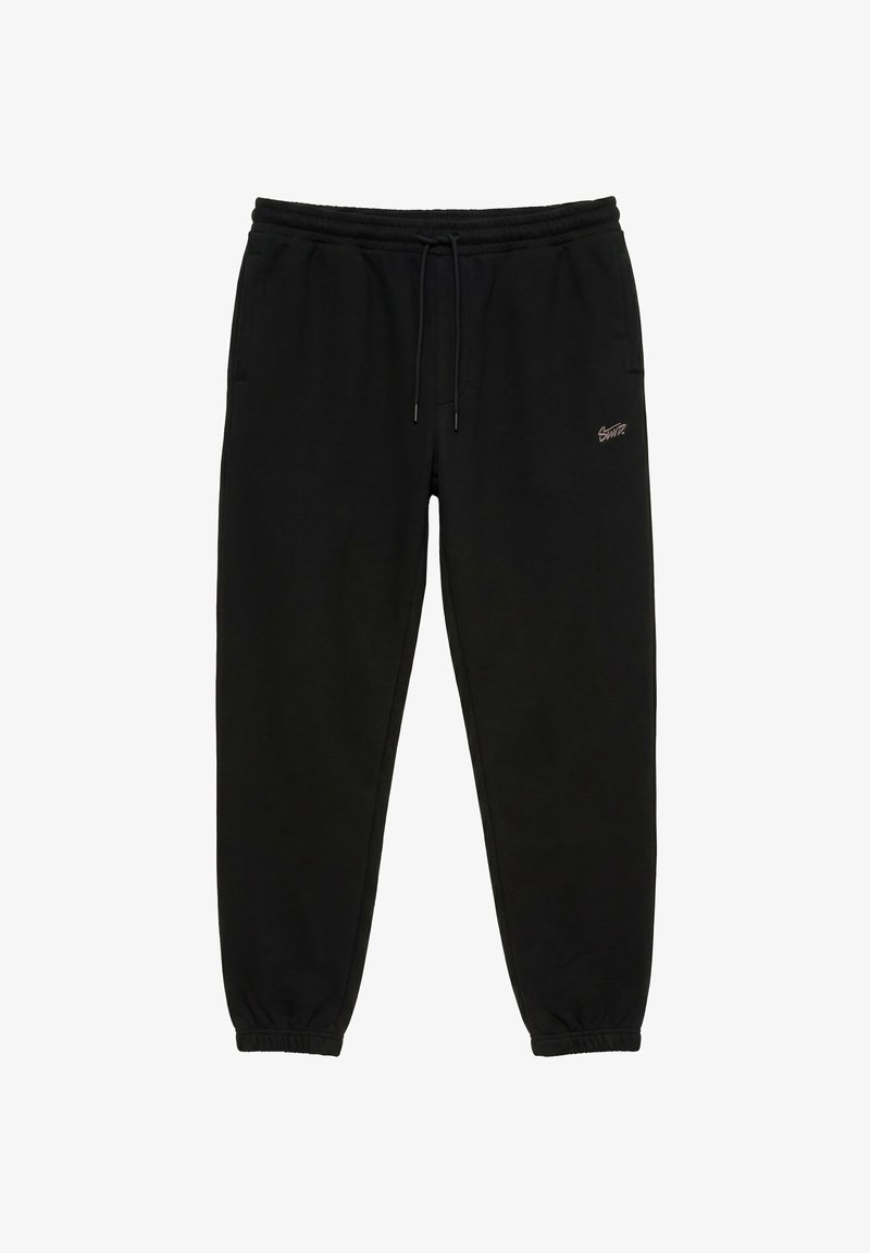 Pantalon de survêtement noir avec taille et poignets élastiques, cordon de serrage, poches latérales et petit logo sur la cuisse droite.