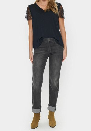 Merihenkinen t-paita pitsiset lyhyet hihat, yhdistetty tummanharmaisiin käärittyihin farkkuihin ja vaaleisiin nilkkakengiin. Tasainen kangas, rento malli.