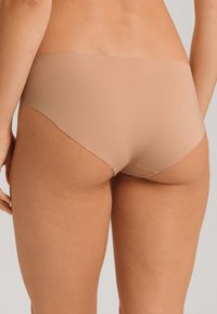 Slip hipster in cotone beige con un design seamless, caratterizzato da una texture morbida e liscia e cuciture minime.