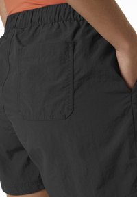 Černé šortky vyrobené z lehkého materiálu, s kapsou na zadní straně a elastickým pasem se shromážděnou texturou.