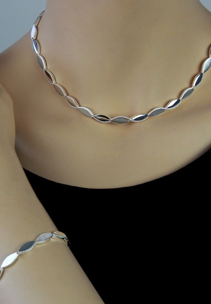 Ensemble de bijoux en argent comprenant un collier et un bracelet avec des maillons ovales, alternant entre des textures polies et brossées.