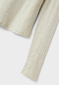 Ljus beige stickad tröja med vertikal ribbning, mjuk textur och subtila dekorativa mönster längs ärmarna och kroppen.