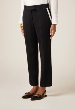 Op maat gemaakte zwarte broek met een rechte pijp, voorzien van een tailleband en zijstrepen. Gemaakt in combinatie met zwart en bruin puntige ballerina's.