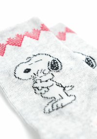 Calzini grigi con un design di Snoopy in bianco e nero. Motivo a zigzag rosso sulla parte superiore. Tessuto morbido con una vestibilità comoda.