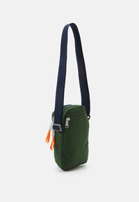 Zielona torba crossbody z granatowym paskiem, z zamykaną kieszonką i jasnopomarańczowymi uchwytami. Prosty prostokątny design.