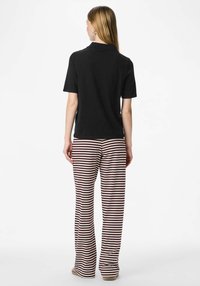 Czarna koszulka polo z krótkim rękawem w połączeniu z szerokimi spodniami w kremowo-bordowe paski, charakteryzującymi się luźnym krojem i miękką teksturą.