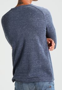 Långärmad skjorta i marinblått, strukturstickad tyg. Rundad halsringning och raglanärmar, med en avslappnad passform och subtil melerat mönster.