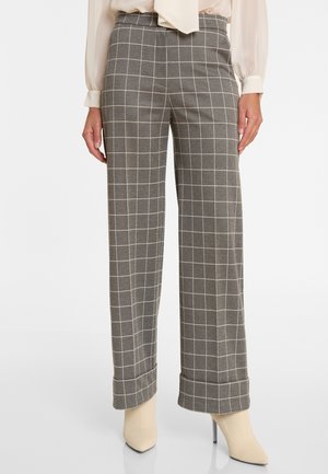 Grijs geruite wijde broek met een gladde textuur, voorzien van een hoge taille en omgeslagen boorden, gecombineerd met beige puntige schoenen.