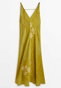 Robe sans manches vert olive avec col en V, fines bretelles, motif en grille diagonale et imprimés floraux beiges à l'avant, suspendue sur fond blanc.