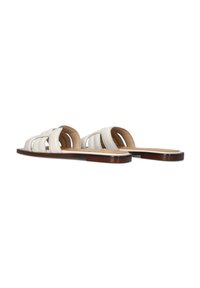 Witte leren slidersandalen met een geweven ontwerp, een vlakke bruine zool en open teen. Kenmerkt een gladde textuur en minimalistische stijl.