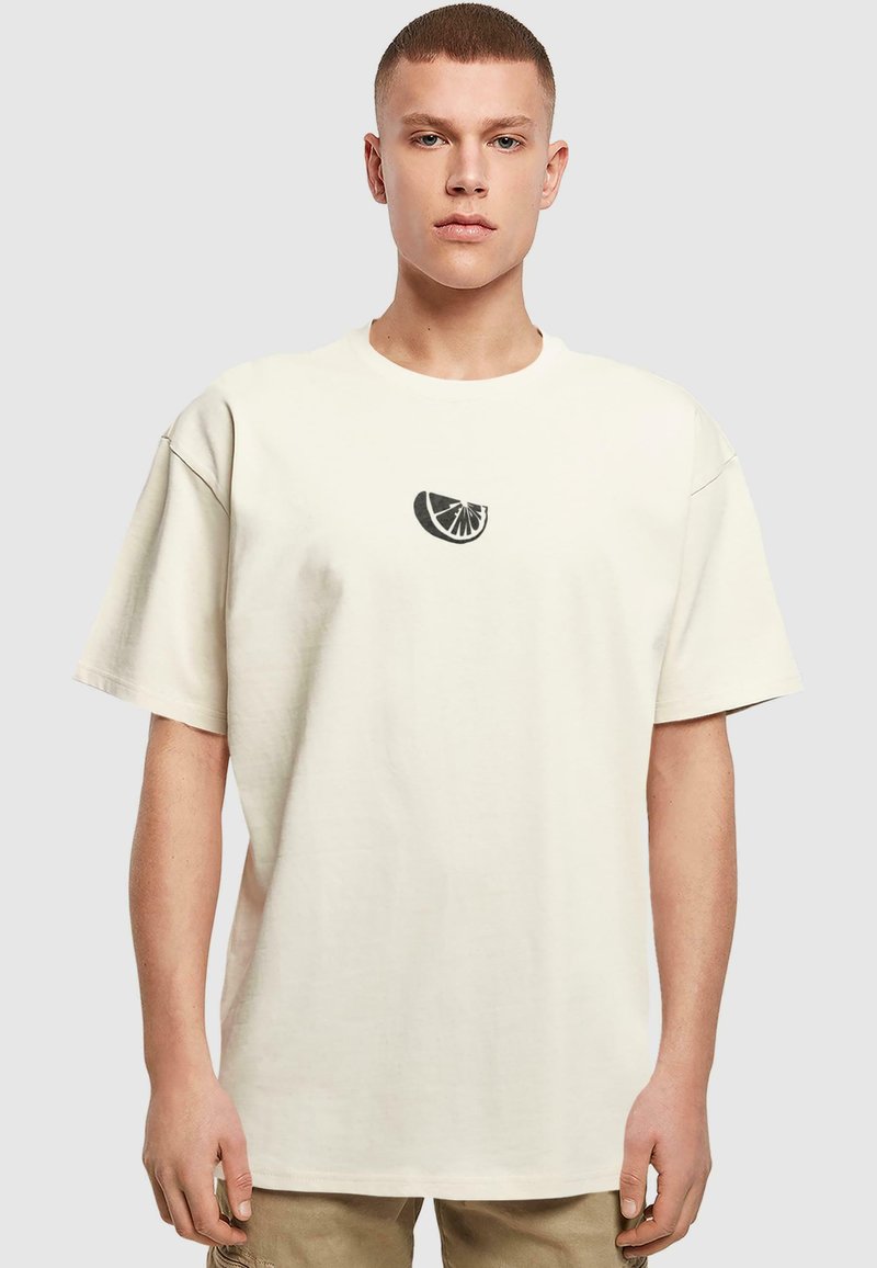 Krämfärgad bomull t-shirt med rund halsringning och korta ärmar. Har en liten svart citrusfrukt-grafik på bröstet.