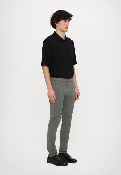 Polo negru cu mânecă scurtă, pantaloni ajustați gri și pantofi negri. Outfit casual, material neted, design structurat, linii curate.
