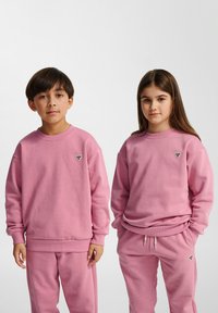 Roze hoodies en bijpassende sweatpants van zacht katoen. Beide hebben ribstof manchetten en een klein geborduurd logo op de borst.