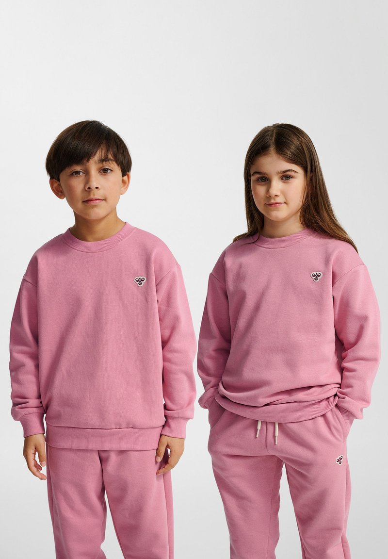 Roze hoodies en bijpassende sweatpants van zacht katoen. Beide hebben ribstof manchetten en een klein geborduurd logo op de borst.