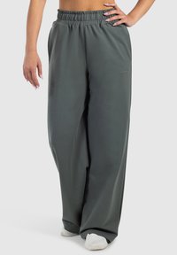 Løst siddende, mørkegrønne sweatpants med elastisk talje og en glat tekstur. Bemærkelsesværdigt hvidt logo på siden og bred ben design.