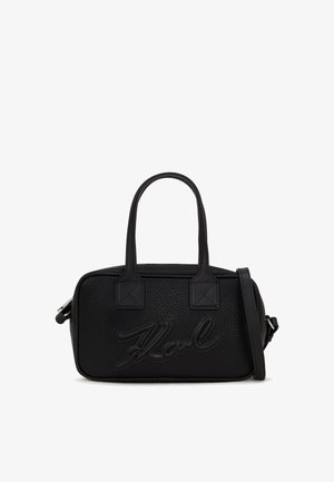 Must mustriga nahast kott kahel käepideme ja reguleeritava õlavarre rihmaga, ees on kujutatud logo detail. Omab nelinurksat kuju.