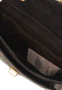 Interno di una borsa in pelle marrone con finitura scamosciata, dotato di una piccola tasca con zip e etichetta di cura, accentuato con hardware dorato.