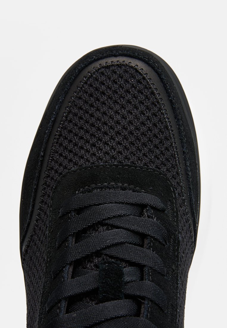 Czarne sneakersy z siateczkową cholewką o teksturowanej powierzchni, płaskimi sznurówkami oraz amortyzującą podeszwą dla wygody. Gładkie syntetyczne akcenty.