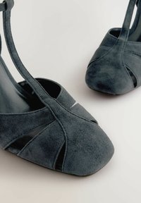 Tummanharmaat mokkanahkahigh heel -kengät, joissa on avonainen varvas, leikattu muotoilu ja kapea nilkkaremmi. Suuri musta vuori.