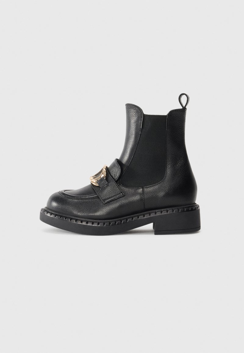 Bottes de cheville en cuir noir avec une finition texturée, des panneaux latéraux élastiques et une boucle décorative en métal doré à l'avant. Semelle épaisse.