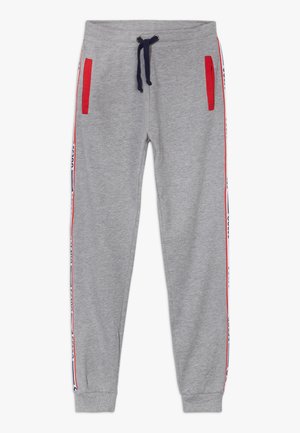 Pantalon de survêtement gris clair avec cordon de serrage bleu marine, poches bordées de rouge et panneaux latéraux rayés rouge et bleu marine avec détails de texte.