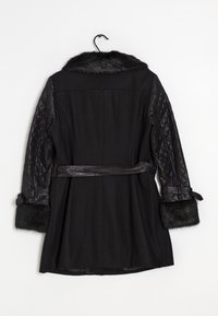 Abrigo negro con cuello y puños de piel sintética, mangas de cuero acolchadas, cintura ceñida con cinturón y falda estructurada. Tejido liso con un brillo sutil.