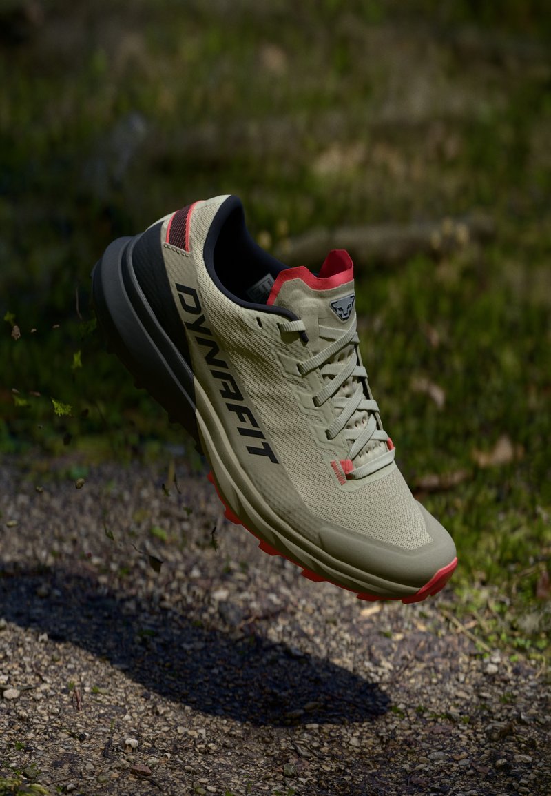 Ανοιχτό καφέ παπούτσι trail running με μαύρες λεπτομέρειες, κόκκινες λεπτομέρειες, πλένει επάνω μέρος και ανθεκτική σόλα, σχεδιασμένο για εξωτερικές διαδρομές.