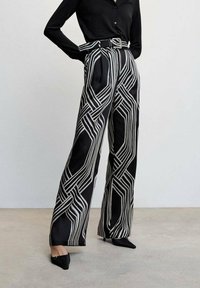 Black wide-legged pants featuring a white geometric pattern. The fabric is smooth with a slight sheen, complemented by a matching belt.